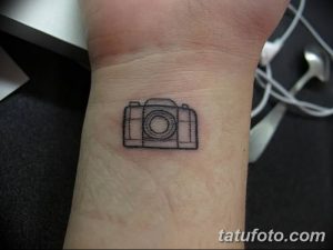 Фото маленькой татуировки фотоаппарата на запястье. Простой контурный рисунок в черно-белом цвете.