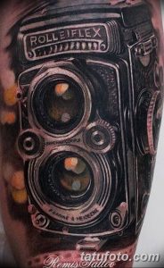 Фото тату с изображением старинного фотоаппарата Rolleiflex, выполненного в реалистичном стиле с высокой детализацией. Татуировка выполнена в черно-серых тонах.