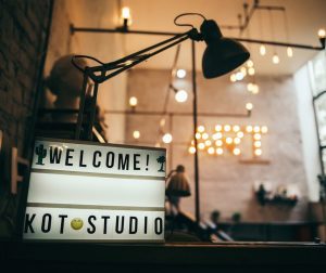 Интерьер тату-студии KOT Studio с неоновой надписью 'WELCOME!' и стильным освещением, создающим уютную атмосферу.