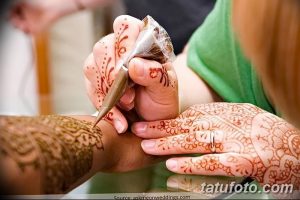 Фото процесса нанесения тату мехенди на руку, демонстрирующее работу мастера с хной и сложный узор, создаваемый на коже.