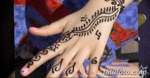 Фото тату мехенди: изящный узор хной на тыльной стороне женской руки, с акцентом на пальцы и запястье. Детализированный рисунок в традиционном стиле.