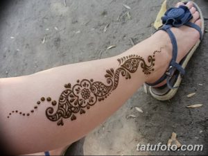 Фото тату мехенди на ноге и стопе, выполненное в коричневых тонах. Сложный узор с цветочными мотивами и геометрическими элементами украшает кожу.