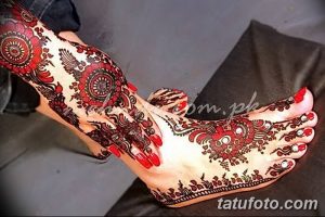Фото тату хной на стопе, с использованием красных и черных оттенков. Сложный узор с цветочными элементами и точками.