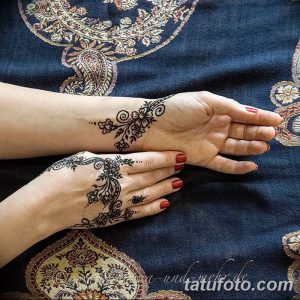 Фото тату хной на руке и предплечье, детальный узор с цветочными мотивами и растительными элементами, выполненный в коричневых тонах.
