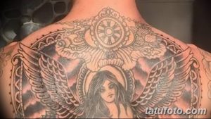 Крупный план татуировки на спине Адама Левина, изображающей ангела с крыльями и черепом, окруженного сложным орнаментом.