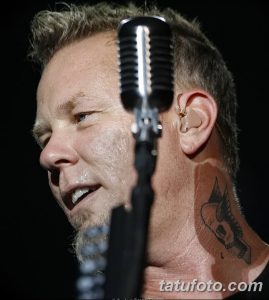 Фотография Джеймса Хетфилда из Metallica, выступающего на сцене с микрофоном. Видна татуировка на его шее.
