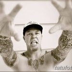 Фотография Джеймса Хетфилда, смотрящего в камеру, с видимыми татуировками на руках и груди.