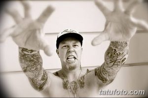 Фотография Джеймса Хетфилда, смотрящего в камеру, с видимыми татуировками на руках и груди.
