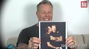 Джеймс Хетфилд держит в руках фотографию, на которой он обнимается с другим человеком, демонстрируя татуировки на руках.