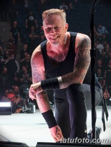 Фотография Джеймса Хетфилда, вокалиста Metallica, во время концерта. Видны детализированные татуировки на руках и плечах музыканта.