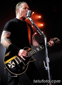 Фотография Джеймса Хетфилда, играющего на гитаре, с акцентом на его татуировки на руках. Видны детализированные рисунки в стиле реализм.