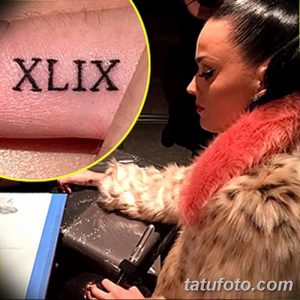 Фото тату: крупный план римских цифр XLIX на пальце певицы Кэти Перри. Черный цвет, небольшое изображение, женская рука.