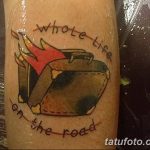Фото тату на руке с изображением горящего чемодана и надписью 'Whole Life on the Road'. Рисунок выполнен в ярких цветах, в стиле олдскул.