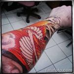 Фотография яркой татуировки дракона на руке. Видны детали рисунка, включая чешую, крылья и когти.