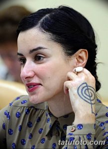 Фото тату на руке: небольшая спираль, выполненная черными чернилами. Эскиз татуировки в стиле минимализм, расположенный на запястье.