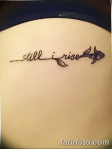 Фото тату с надписью 'still i rise' и изображением пера на спине. Минималистичный и вдохновляющий рисунок, выполненный хной.