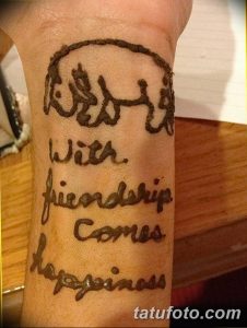 Татуировка на руке с надписью "With friendship comes happiness" (С дружбой приходит счастье) и изображением двух рук.