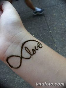 Простая и элегантная татуировка на запястье, изображающая слово "Love" внутри символа бесконечности.