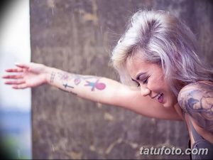 Фото тату на руке девушки, разноцветные рисунки, крест, сердце, птица, дождь, бледные волосы, портрет.