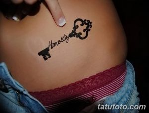 Фото татуировки на бедре, изображающей старинный ключ, на котором написано слово "Honesty". Стиль - графика, выполненная в черном цвете.