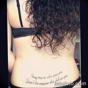 Фото тату надписи "Stay true to who you are Don’t let anyone else define you" на спине девушки.