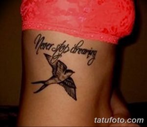 Фото тату на коже, изображающее летящую ласточку и надпись "Never stop dreaming". Небольшой рисунок татуировки в черном цвете.
