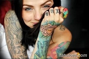 Фотография девушки с татуировками на руках и пальцах. Видны татуировки с изображением роз и надписей.