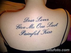 Фото тату надписи 'Dear Lover, Give Me One Last Painful Kiss' на женской спине. Элегантный шрифт, выполненный черными чернилами. Расположена между лопатками.