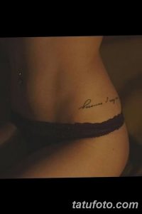 Фото тату надписи 'Because I am' на женской талии. Изящный шрифт, выполненный черными чернилами. Минималистичный дизайн, подчеркивающий изгибы тела.