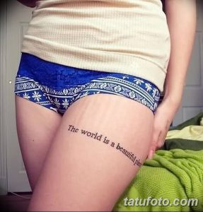Фото тату: надпись "The world is a beautiful place" на бедре девушки. Татуировка выполнена простым шрифтом.