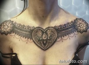 Фото тату: черная татуировка в стиле мандала, расположенная на груди и плечах женщины. Детализированный рисунок с геометрическими узорами и сердцевидным центром.