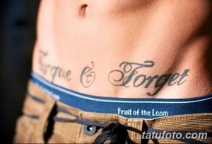 Фото тату надписи 'Forgive & Forget' на талии. Черно-серый рисунок татуировки выполнен каллиграфическим шрифтом, лаконичный дизайн.