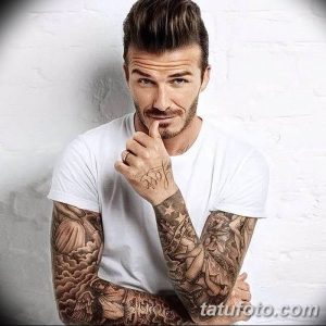 Фотография Дэвида Бекхема с татуировками на руках и надписью 'Love' на тыльной стороне ладони. Рисунки выполнены в черно-белой гамме.