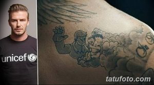 Фото тату Дэвида Бекхема на плече. Изображен ангел, держащий на руках ребенка, выполненный в черно-белом стиле. Детализированный рисунок татуировки.