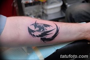 Черно-белая татуировка ворона на предплечье, выполненная в графическом стиле. Изображение простое, но выразительное, с четкими линиями и минимальным количеством деталей.