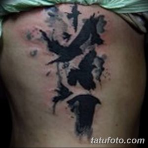 Фото акварельной татуировки ворона на спине. Черно-серая татуировка с размытыми краями и эффектом акварели.