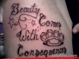 Фото татуировки кастета с надписью 'Beauty Comes With Consequences' на руке. Рисунок выполнен в черно-серых тонах с использованием четких контуров и декоративных элементов.