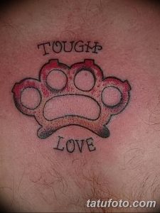 Татуировка кастета с надписями "TOUGH" и "LOVE". Рисунок выполнен в простом стиле, с использованием красных и черных цветов.