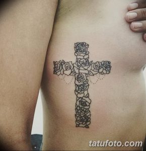 Фотография татуировки на груди, изображающей крест, образованный из роз. Татуировка выполнена в черно-белых тонах с детализированной проработкой лепестков.
