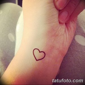 Фото тату маленького черного сердца на запястье девушки. Простой и минималистичный рисунок татуировки, популярный выбор для первого тату.