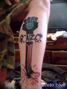 Фото тату на ноге с изображением руки, держащей кинжал, и надписью 'GONZO'. Черно-красный рисунок татуировки в стиле графика.