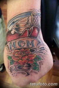 Фото тату на ноге с изображением сердца, розы и надписи 'MOM'. Цветной рисунок татуировки в стиле олд скул.