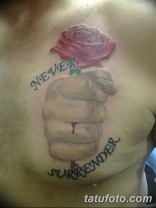 Фото татуировки на груди: пронзенное сердце с розой сверху и надписями 'NEVER' и 'SURRENDER'.