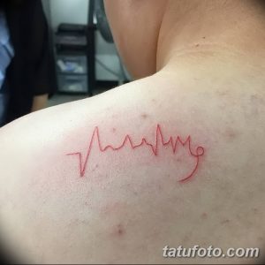 Фото тату кардиограммы на плече, выполненное красными тонами. Изображение выглядит минималистично и элегантно.