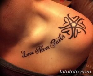 Фото тату на груди: надпись "Love Never Fails" в каллиграфическом стиле и кельтский узор.