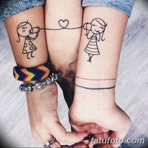 Фотография двух запястий с парными татуировками, изображающими схематичные фигурки людей, соединенных тонкой линией, символизирующей связь.