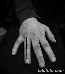 Фото тату: очень тонкая, черная линия, нанесенная вдоль пальца руки, минималистичный дизайн.