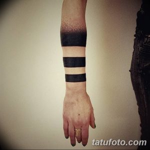 Черно-белое фото тату на запястье, изображающее несколько черных полос разной ширины. Геометрический и минималистичный рисунок татуировки.