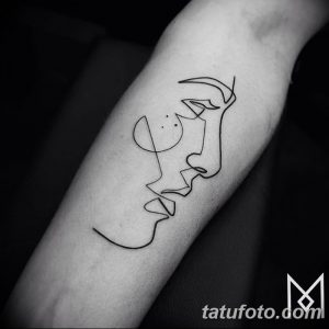 Черно-белое фото тату на предплечье, изображающее лицо и профиль, выполненное тонкими линиями. Минималистичный рисунок татуировки.