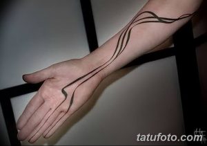 Фото татуировки на руке, представляющей собой несколько черных линий, изящно переплетающихся между собой. Минималистичный и стильный рисунок татуировки.